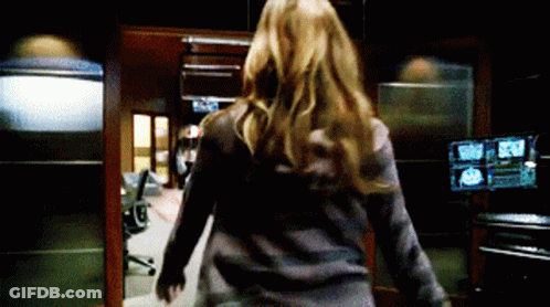 A Woman Is Walking Through A Room With A Lot Of Monitors . GIF