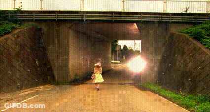 A Woman Is Walking Under A Bridge On A Road . GIF