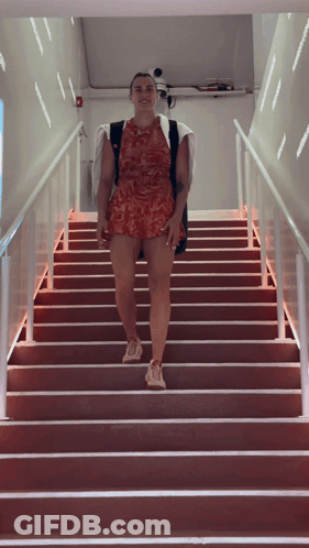 A Woman Is Walking Up A Set Of Stairs GIF