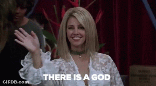 A Woman Is Waving Her Hand And Smiling While Standing In Front Of A Red Curtain . GIF
