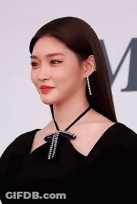A Woman Is Wearing A Black Dress And Earrings . GIF