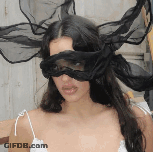 A Woman Is Wearing A Black Mask On Her Eyes GIF