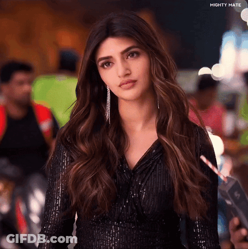 A Woman Is Wearing A Black Sequined Top And Holding A Straw In Her Hand .. GIF