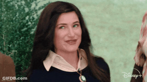 A Woman Is Wearing A Black Shirt And A Necklace With A Disney Logo On It . GIF