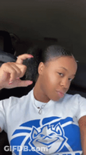 A Woman Is Wearing A Blue And White Shirt With A Duke Logo On It . GIF