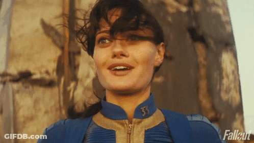 A Woman Is Wearing A Blue Jacket With The Letter T On It GIF