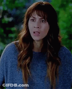 A Woman Is Wearing A Blue Sweater And Making A Funny Face . GIF