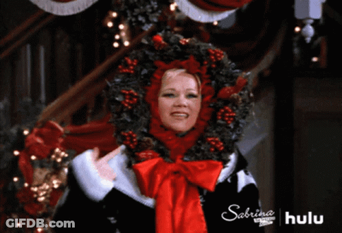 A Woman Is Wearing A Christmas Wreath On Her Head And The Words Sabrina On The Bottom Right GIF