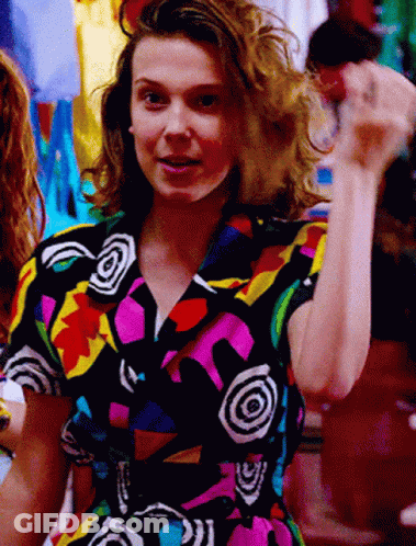 A Woman Is Wearing A Colorful Shirt With A Swirl Pattern GIF