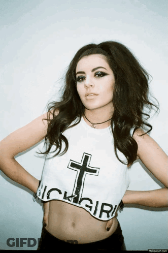 A Woman Is Wearing A Crop Top With A Cross On It And The Word Girl On It GIF