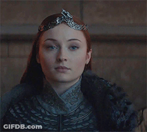 A Woman Is Wearing A Crown On Her Head And Looking At The Camera . GIF