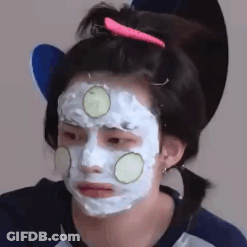 A Woman Is Wearing A Face Mask With Cucumber Slices On It . GIF