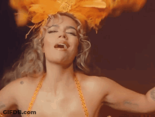 A Woman Is Wearing A Feathered Headpiece And Dancing GIF