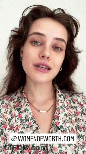 A Woman Is Wearing A Floral Shirt And A Necklace With The Website Womenofworth.com Written Below Her GIF
