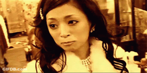 A Woman Is Wearing A Fur Coat And A Necklace And Looking At The Camera . GIF