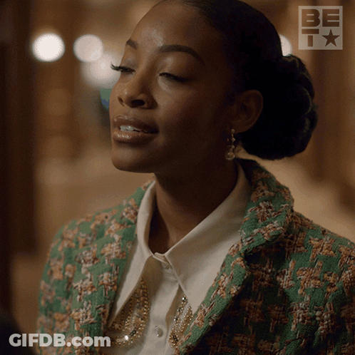 A Woman Is Wearing A Green Jacket And A White Shirt With A Be Logo In The Background GIF