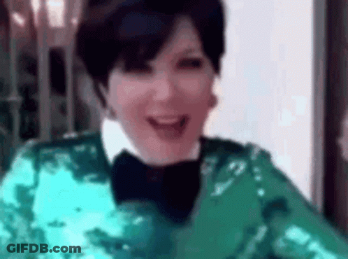 A Woman Is Wearing A Green Sequined Jacket And A Black Bow Tie . GIF