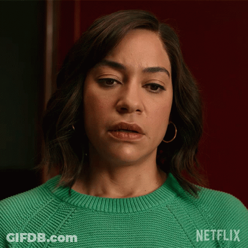 A Woman Is Wearing A Green Sweater With Netflix Written On It GIF