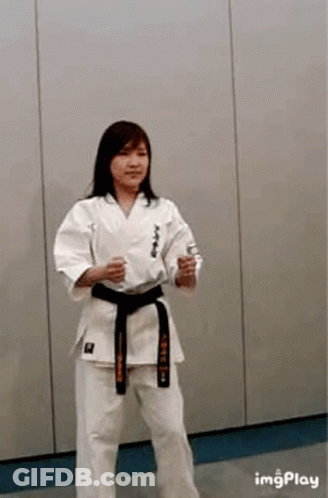 A Woman Is Wearing A Karate Uniform And A Black Belt . GIF