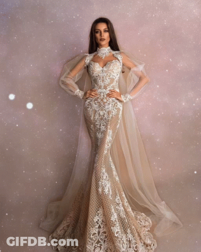 A Woman Is Wearing A Long White Dress With A Cape GIF