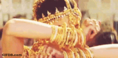 A Woman Is Wearing A Lot Of Gold Jewelry And Dancing . GIF