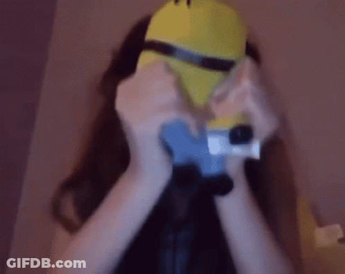 A Woman Is Wearing A Minion Mask And Holding A Camera GIF
