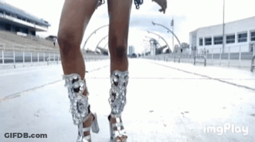 A Woman Is Wearing A Pair Of Silver High Heels . GIF