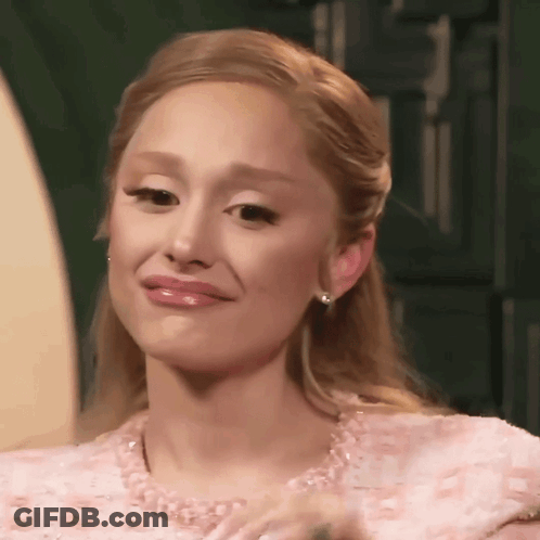 A Woman Is Wearing A Pink Dress And Earrings And Making A Funny Face . GIF