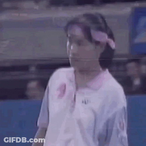 A Woman Is Wearing A Pink Headband And A White Shirt . GIF