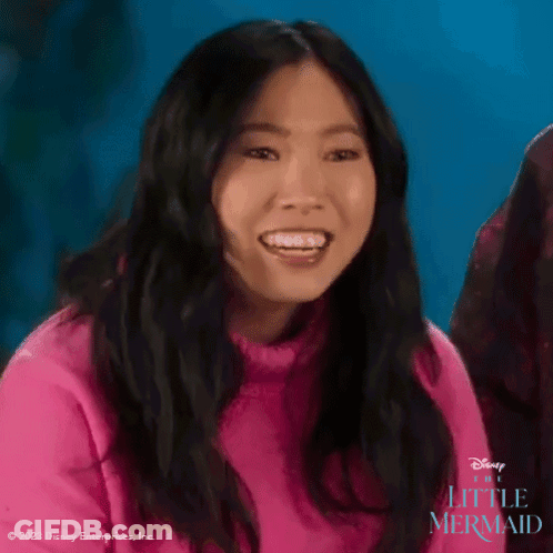 A Woman Is Wearing A Pink Sweater And Smiling For The Little Mermaid GIF