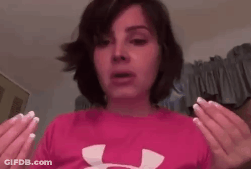 A Woman Is Wearing A Pink Under Armour Shirt And Holding Her Hands Up In The Air . GIF