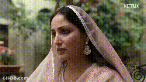 A Woman Is Wearing A Pink Veil And Earrings And Looking At The Camera . GIF