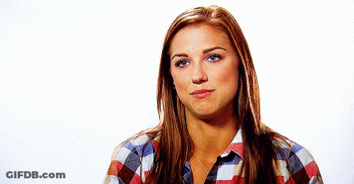 A Woman Is Wearing A Plaid Shirt And Making A Face . GIF