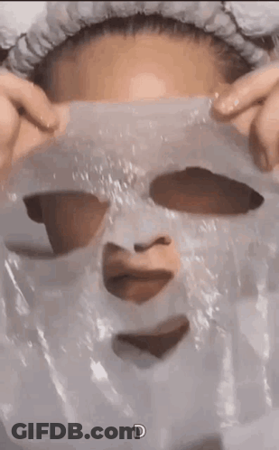 A Woman Is Wearing A Plastic Mask On Her Face With A Heart Cut Out Of It . GIF