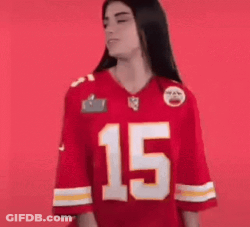 A Woman Is Wearing A Red Kansas City Chiefs Jersey And Smiling . GIF