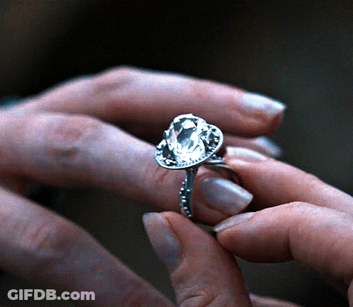 A Woman Is Wearing A Ring With A Large Diamond In It GIF