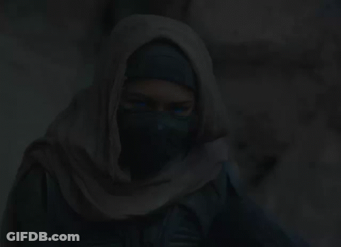 A Woman Is Wearing A Scarf Around Her Head In The Dark GIF
