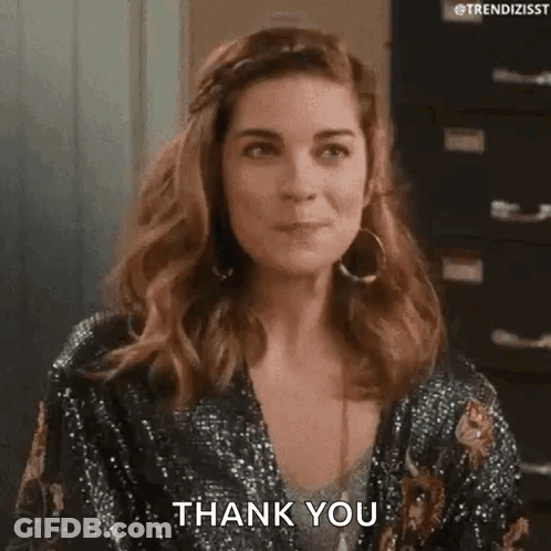 A Woman Is Wearing A Sequined Jacket And Earrings And Is Saying Thank You . GIF