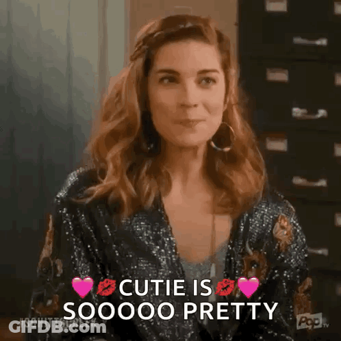 Woman In Sequined Jacket And Earrings Says Cutie Is Pretty GIF