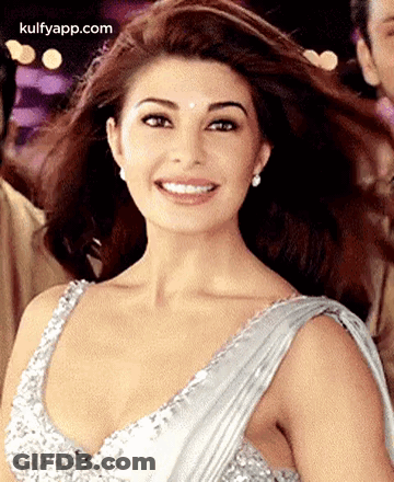 A Woman Is Wearing A Silver Dress And Smiling . GIF