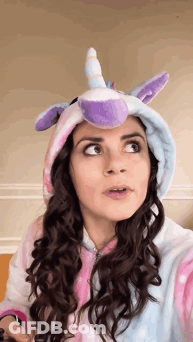 A Woman Is Wearing A Unicorn Costume With A Purple Horn On Her Head . GIF