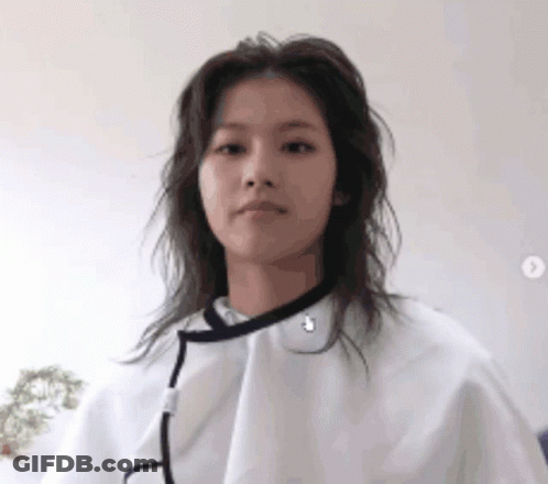A Woman Is Wearing A White Cape Over Her Head And Looking At The Camera . GIF