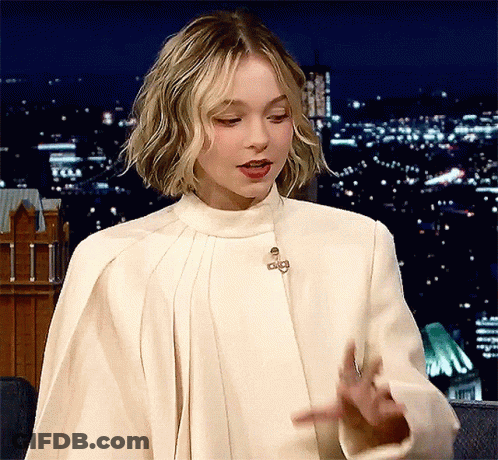 A Woman Is Wearing A White Coat With A Collar And A Cape .. GIF