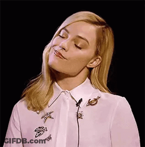A Woman Is Wearing A White Shirt With Brooches On It And A Microphone In Her Neck . GIF