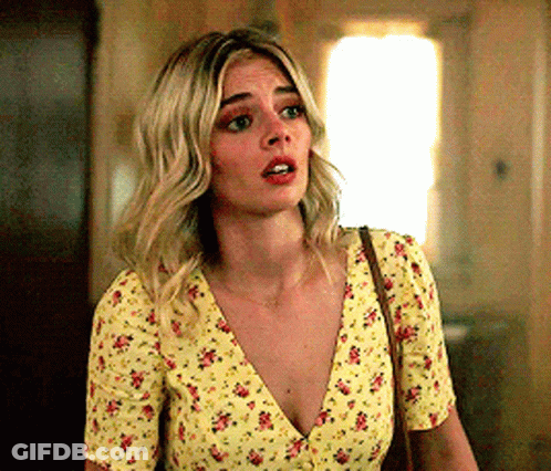 A Woman Is Wearing A Yellow Floral Top And A Brown Purse . GIF