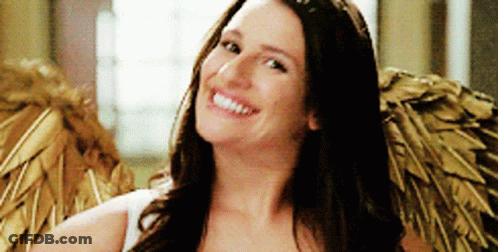 A Woman Is Wearing Angel Wings And Smiling For The Camera GIF