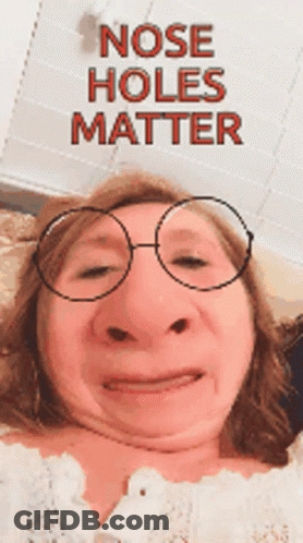A Woman Is Wearing Glasses And Making A Funny Face With The Words Nose Holes Matter Behind Her GIF