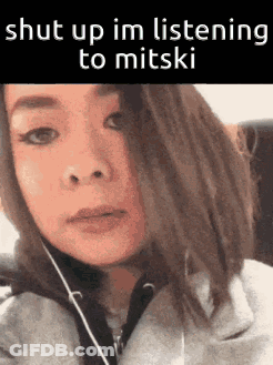 A Woman Is Wearing Headphones And Says Shut Up Im Listening To Mitski . GIF