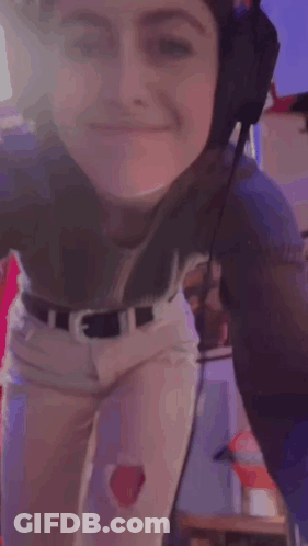 A Woman Is Wearing Headphones And Smiling While Dancing . GIF