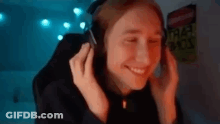A Woman Is Wearing Headphones And Smiling While Sitting In Front Of A Computer Screen . GIF
